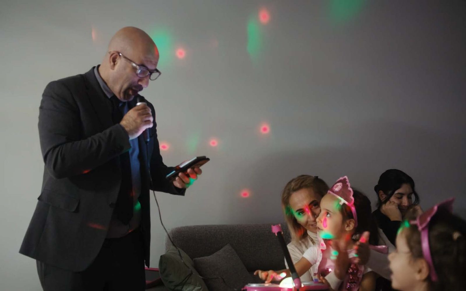 Tayfun singt Karaoke, umgeben von seinen Töchtern